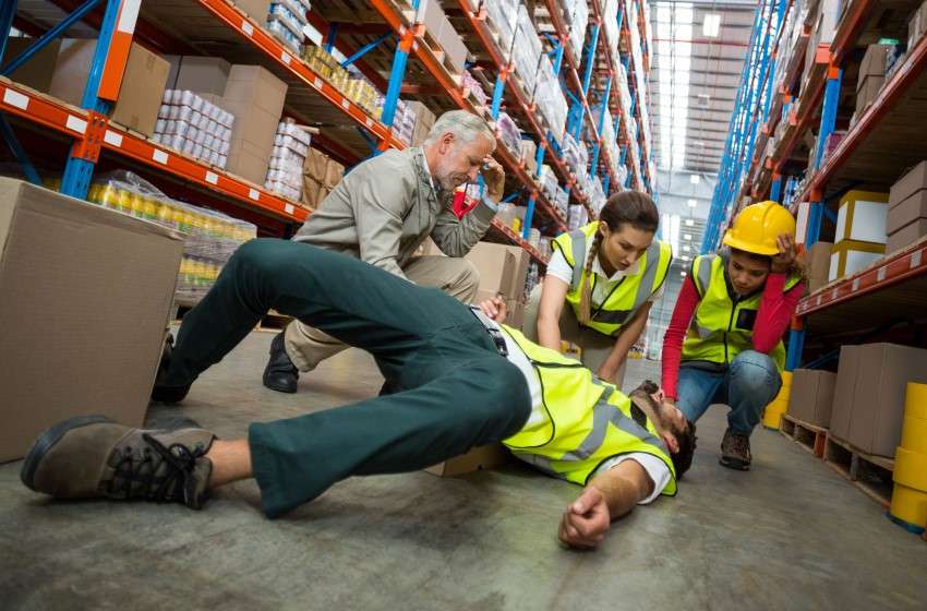 Picture of a worker injured on the ground holding his lower back before he consults with a workers comp lawyer